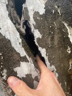 A crack in a concrete tank wall, wide enough to fit a finger into